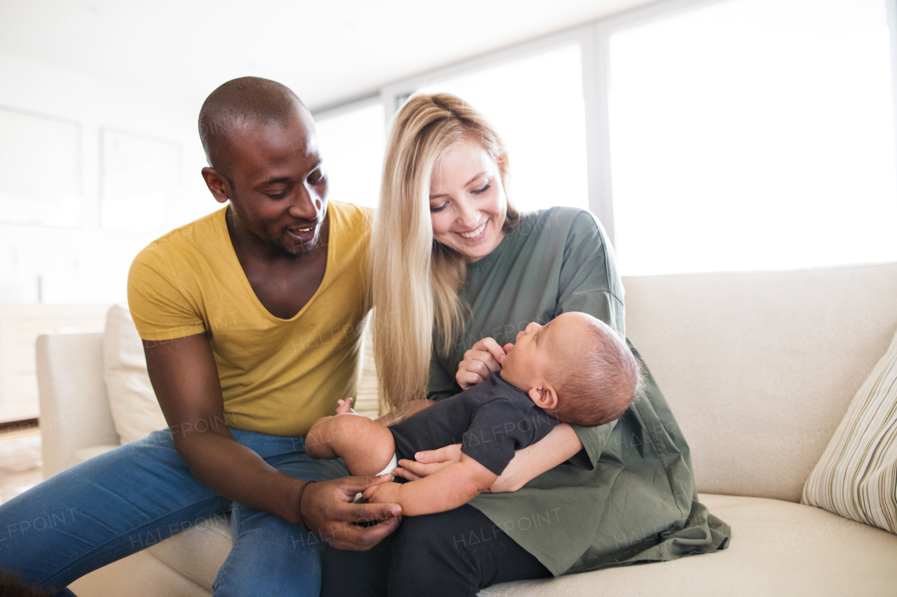 Beautiful young interracial family at home holding their cute little baby son.