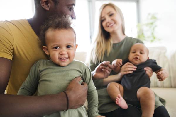 Beautiful young interracial family at home with their cute daughter and little baby son.