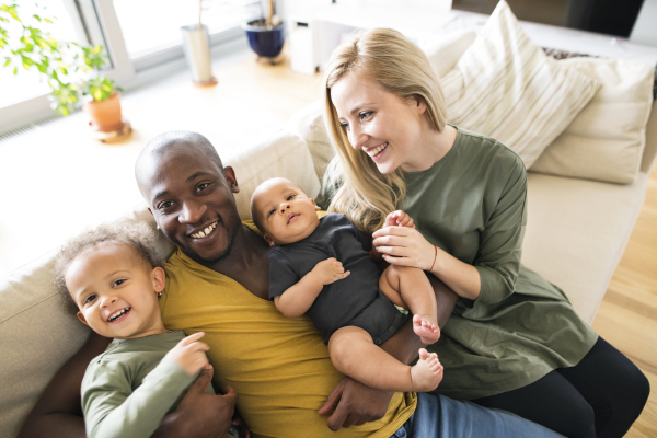 Beautiful young interracial family at home with their cute daughter and little baby son.