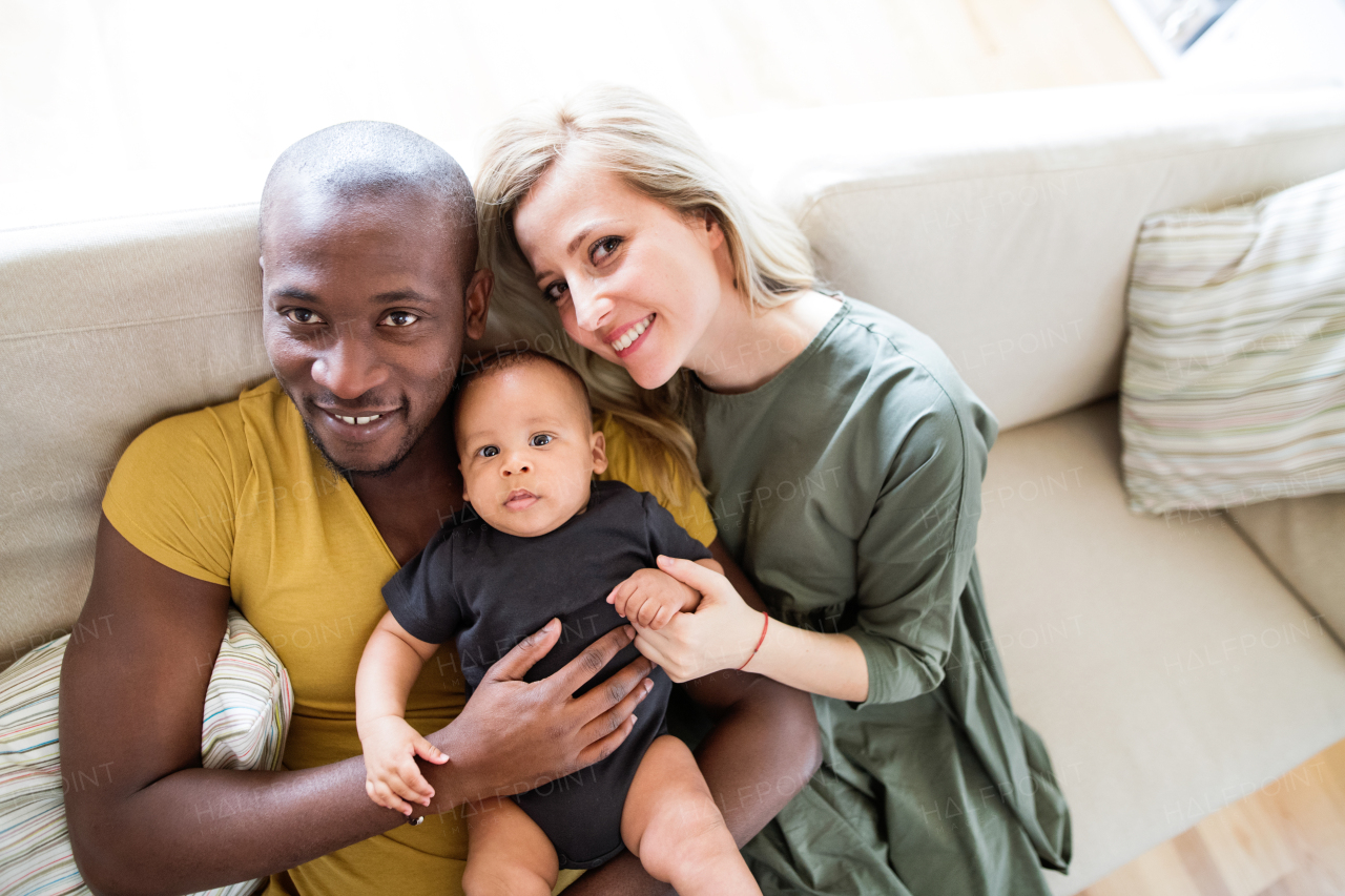 Beautiful young interracial family at home holding their cute little baby son.