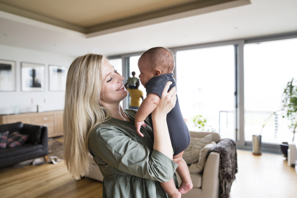 Young mother with her little son holding her in arms at home.