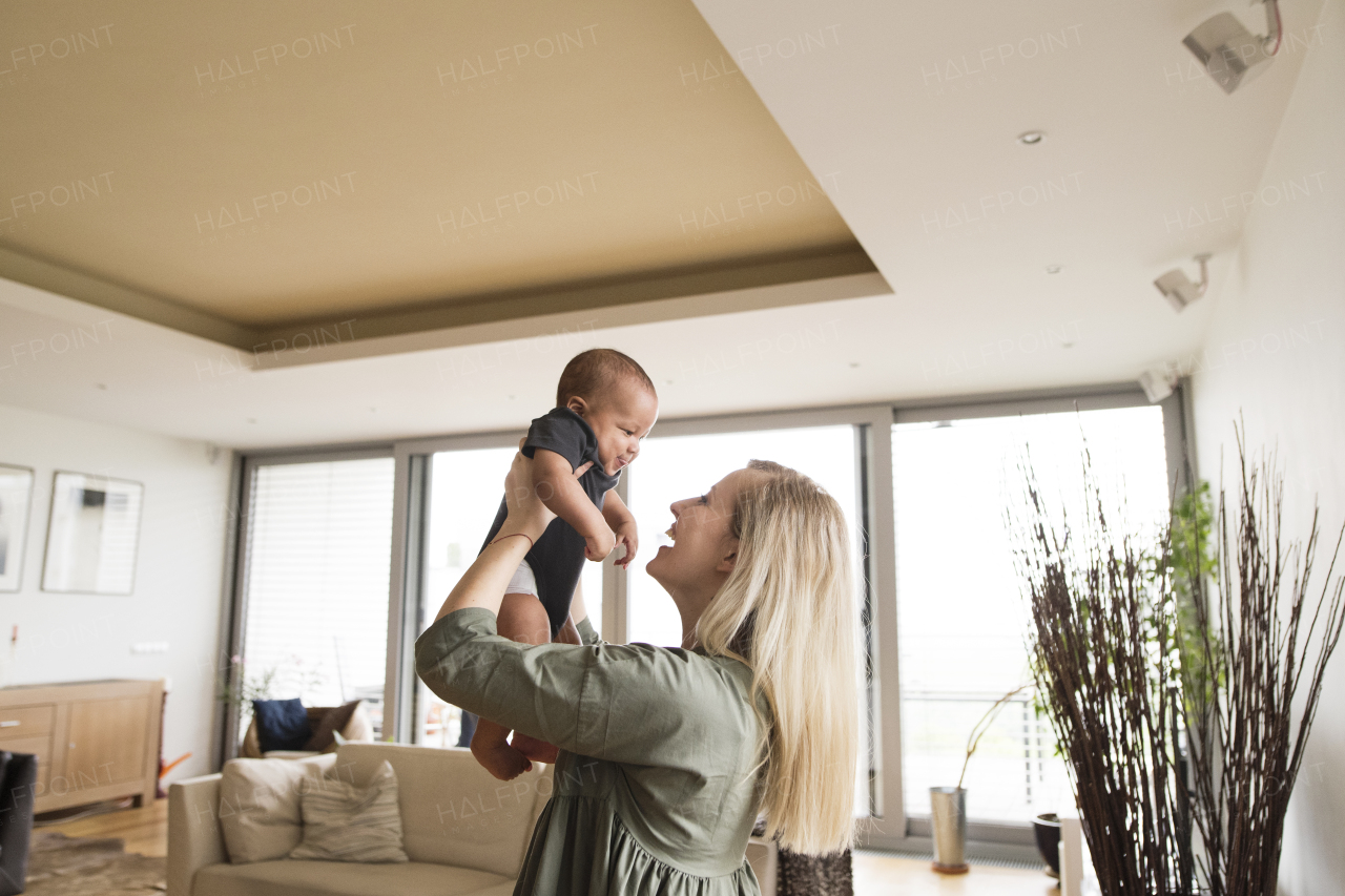 Beautiful young mother holding her little baby son in the arms at home.