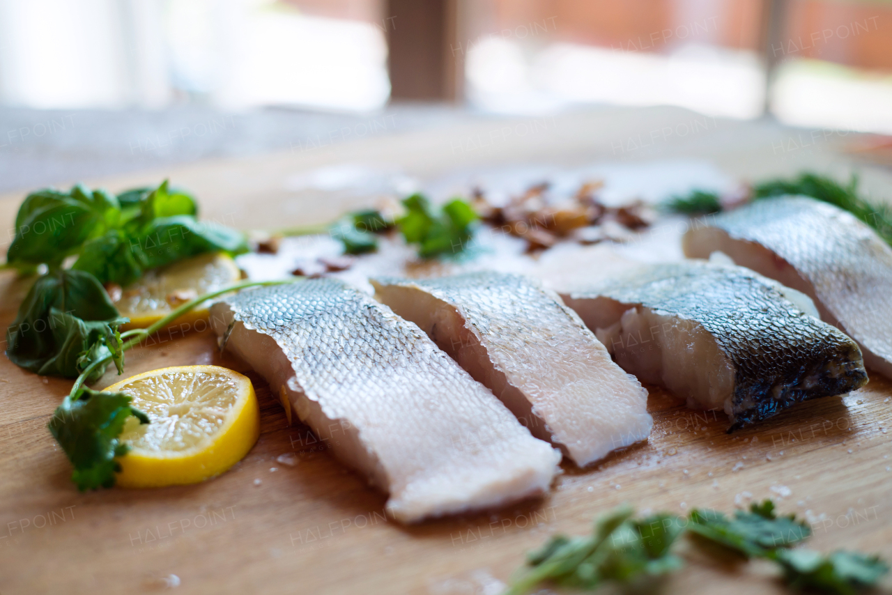 Raw zander fish fillets with lemon slices and herbs on a wooden cutting board.