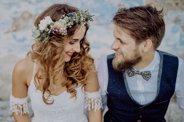 Beautiful young bride and groom outside in front of an old shabby house.