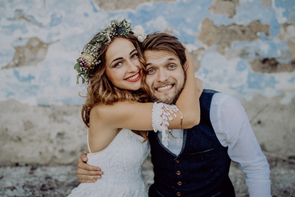 Beautiful young bride and groom outside in front of an old shabby house.