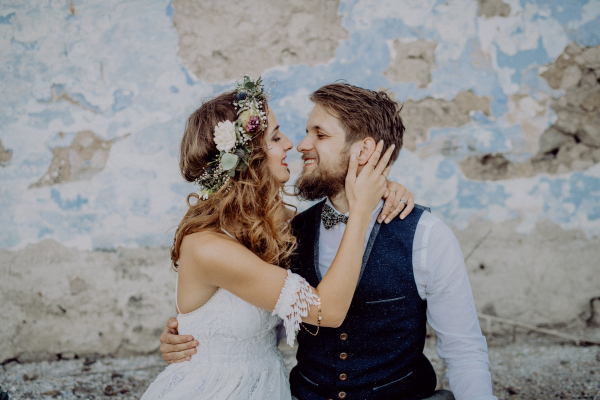 Beautiful young bride and groom outside in front of an old shabby house.