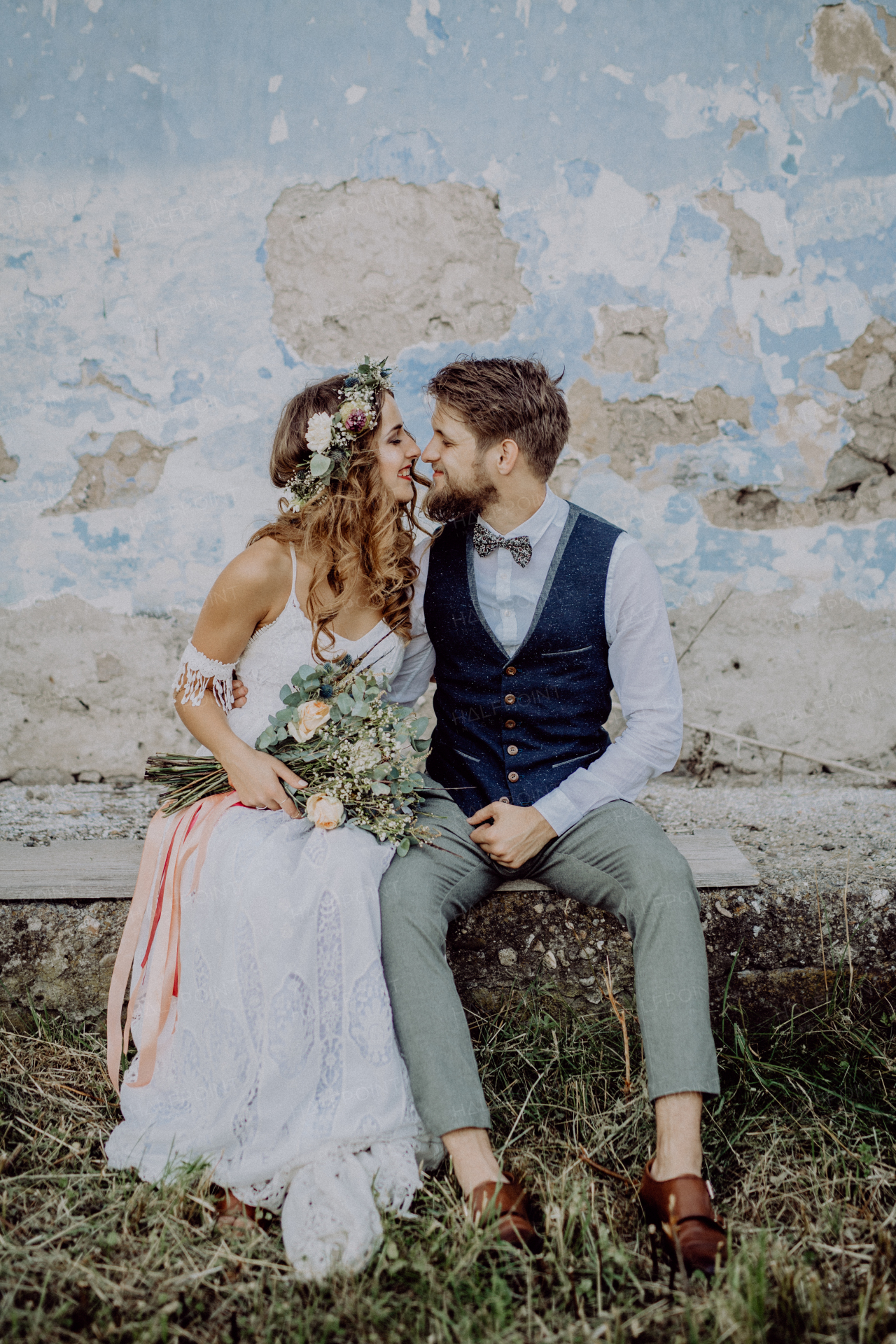 Beautiful young bride and groom outside in front of an old shabby house.