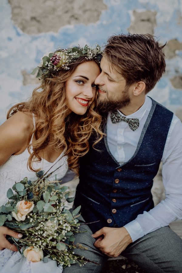 Beautiful young bride and groom outside in front of an old shabby house.