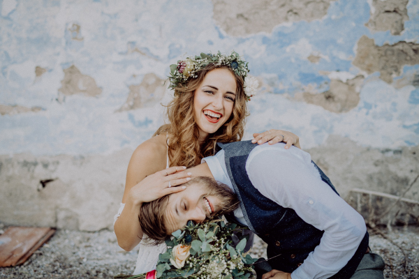 Beautiful young bride and groom outside in front of an old shabby house.