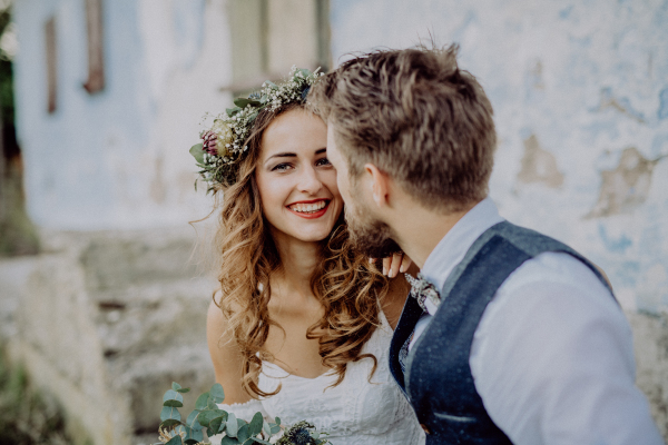 Beautiful young bride and groom outside in front of an old shabby house.