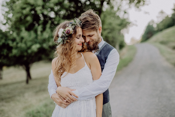 Beautiful young bride and groom hugging outside in green nature.