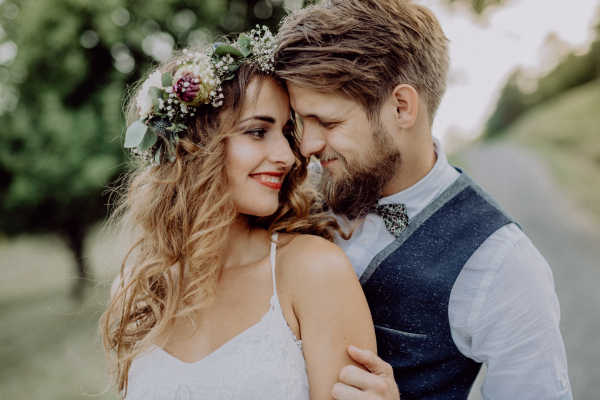 Beautiful young bride and groom hugging outside in green nature.