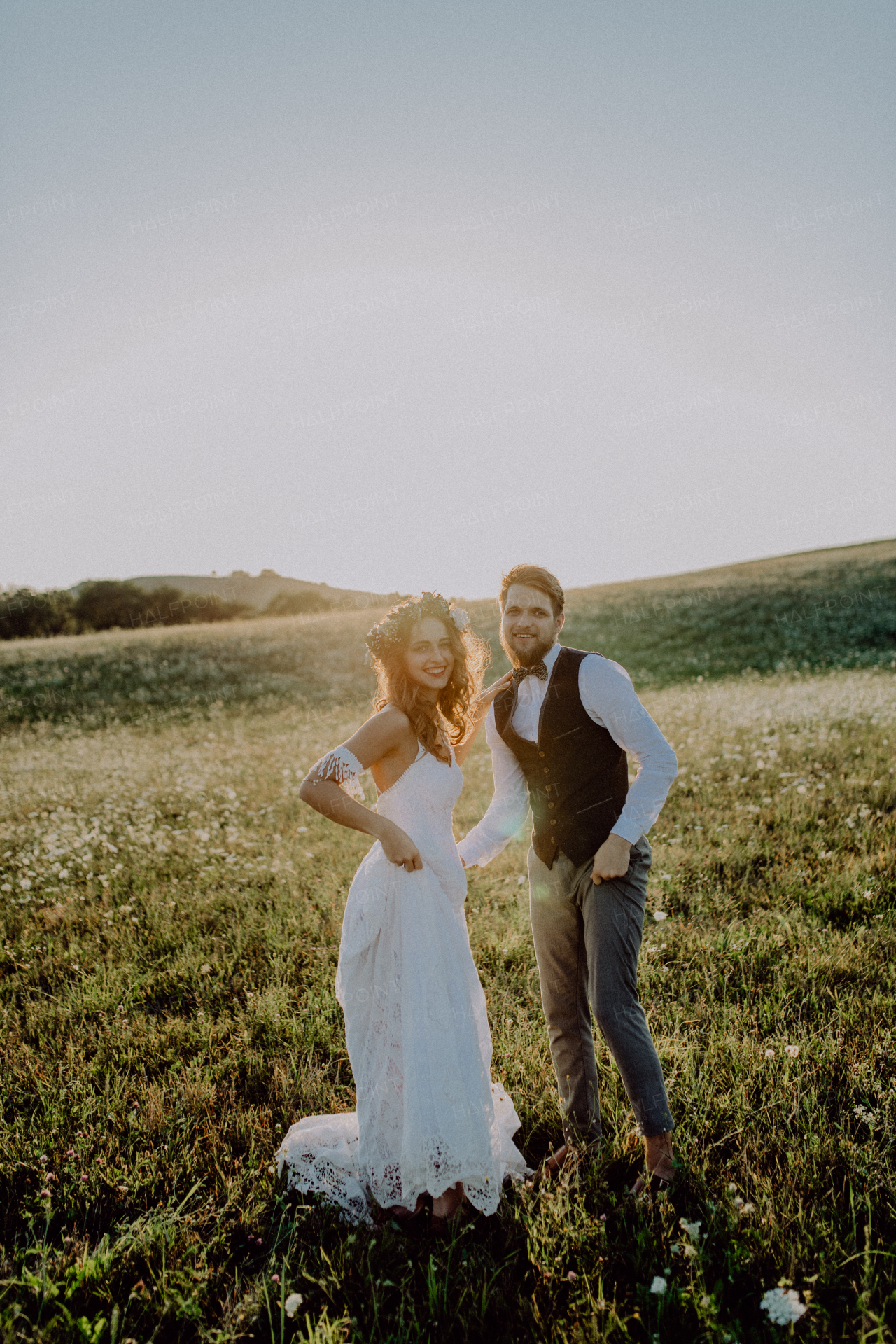 Beautiful young bride and groom outside in green nature at romantic sunset.