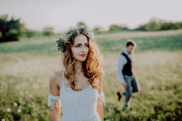 Beautiful young bride and groom outside in green nature at romantic sunset.