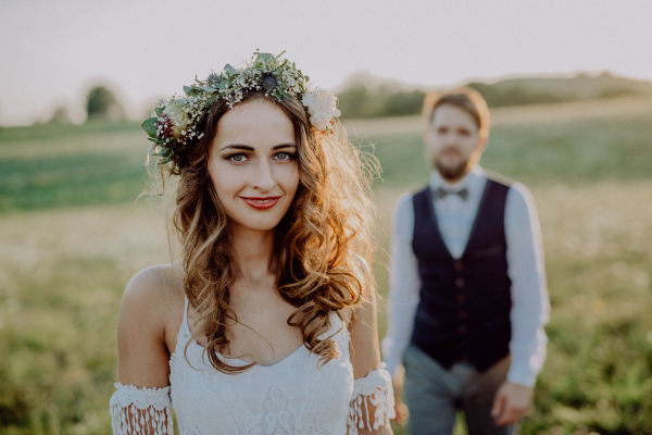 Beautiful young bride and groom outside in green nature at romantic sunset.