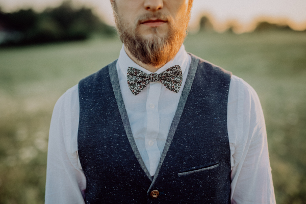 Handsome young groom posing outside in nature