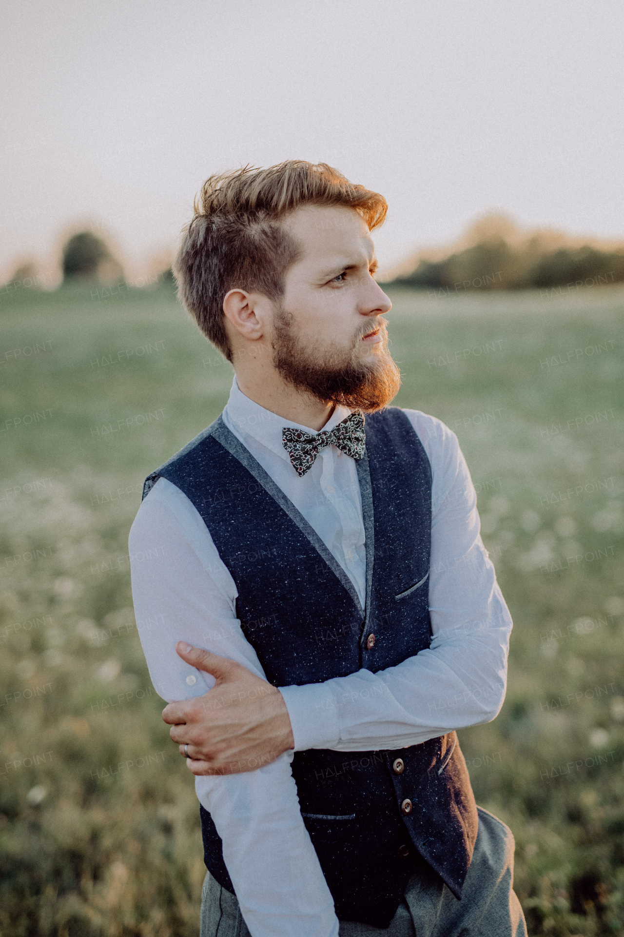 Handsome young groom posing outside in nature.