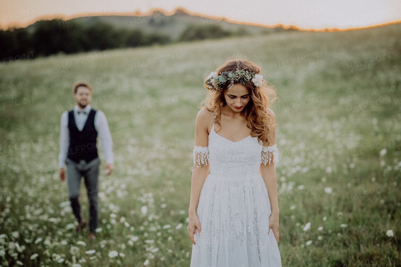 Beautiful young bride and groom outside in green nature at romantic sunset.