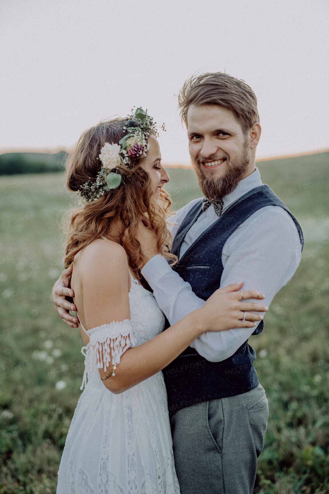 Young bride and groom outside in green nature at romantic sunset.