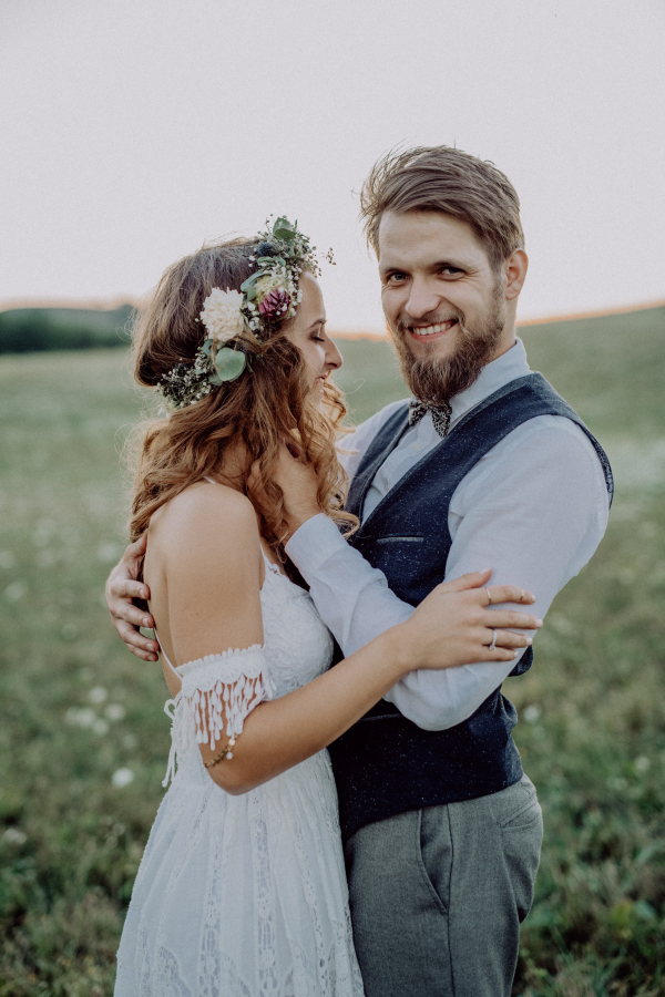 Young bride and groom outside in green nature at romantic sunset.