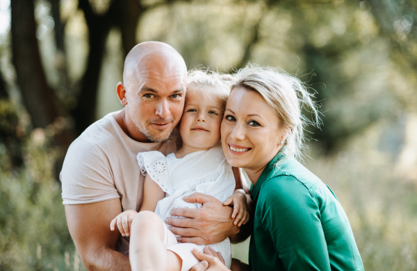 Young family with a small daughter spending time together in sunny summer nature.