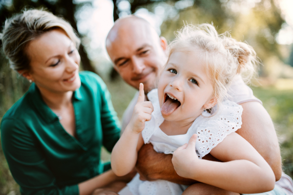 Young family with a small daughter spending time together in sunny summer nature.