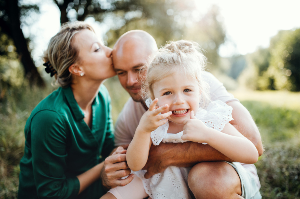 Young family with a small daughter spending time together in sunny summer nature.