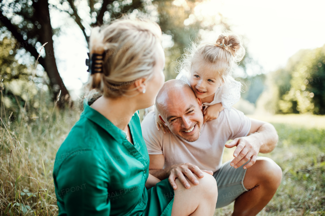 Young family with a small daughter spending time together in sunny summer nature.