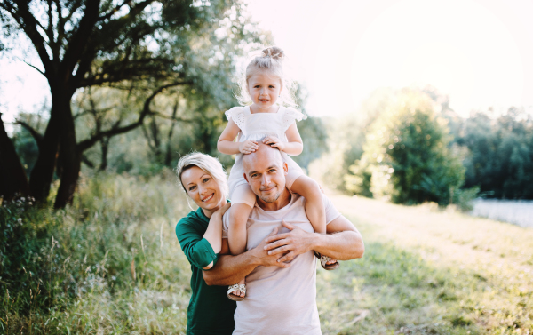 Young family with a small daughter spending time together in sunny summer nature.