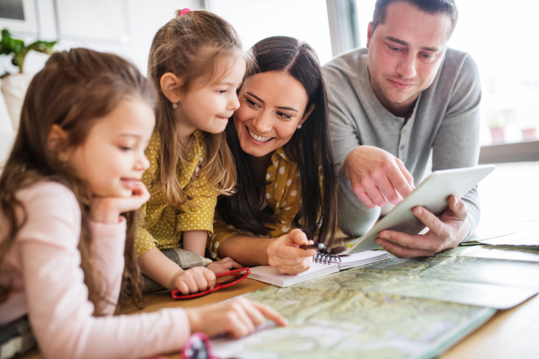 Young happy family with two children and tablet preparing for holidays at home.