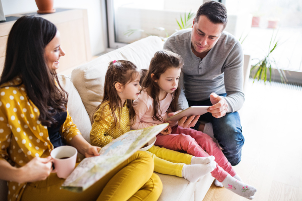 Portrait of a young happy family with two children preparing for holiday at home. A man using tablet.