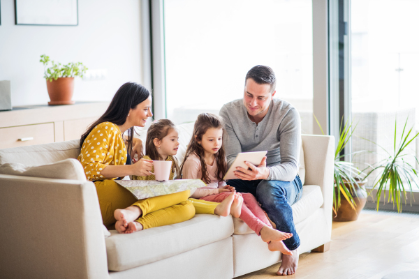 Portrait of a young happy family with two children preparing for holiday at home. A man using tablet.