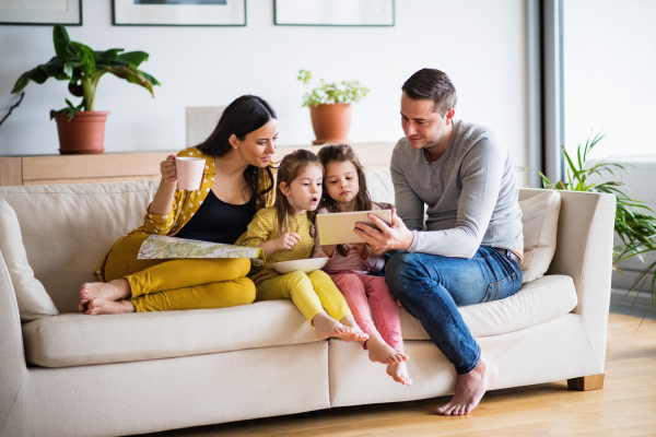 Portrait of a young happy family with two children preparing for holiday at home. A man using tablet.