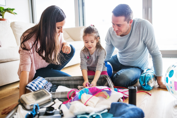 Portrait of a young happy family with a child packing for holiday at home.