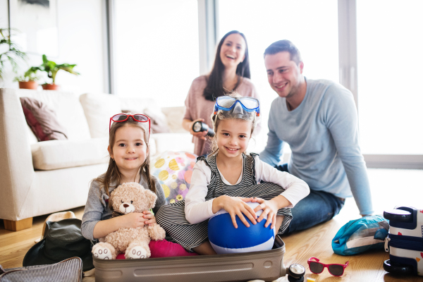 Portrait of a young happy family with two children packing for holiday at home.