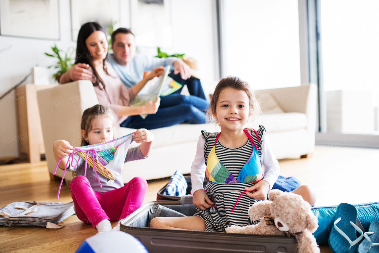 Portrait of a young happy family with two children packing for holiday at home.