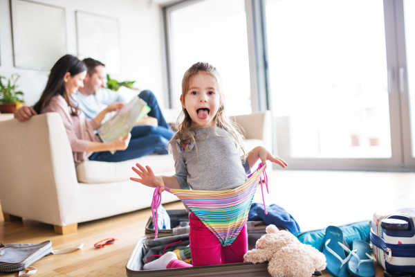 Young happy family with a small child packing for holiday at home.