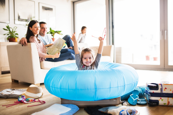 Portrait of a young happy family with two children packing for holiday at home.