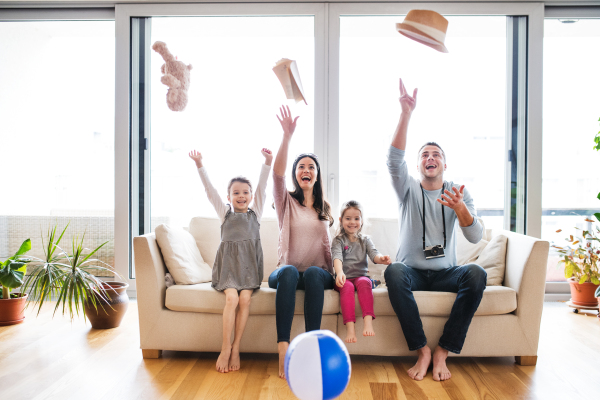 Portrait of a young happy family with two children packing for holiday at home, having fun.