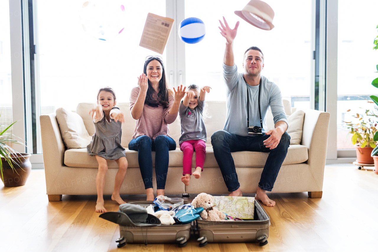 Portrait of a young happy family with two children packing for holiday at home.