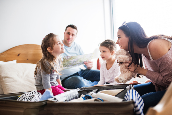 Portrait of a young happy family with two children packing for holiday at home.