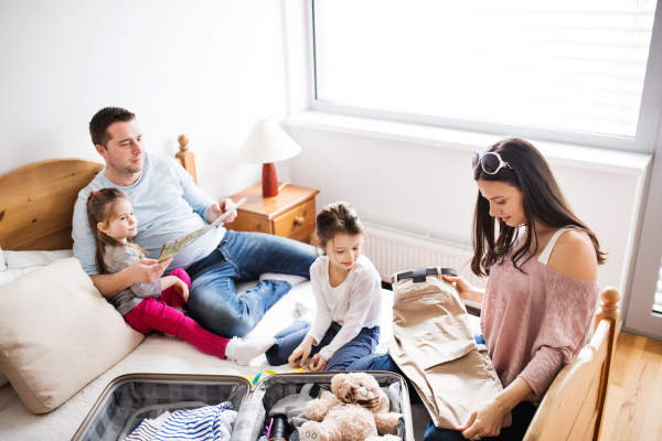 Portrait of a young happy family with two children packing for holidays at home.