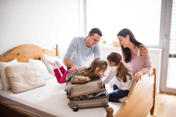 Portrait of a young happy family with two children packing for holidays at home.