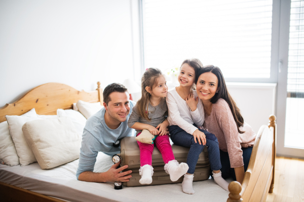 Portrait of a young happy family with two children packing for holiday at home.