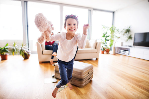 Young happy child with parents in the background packing for holidays at home.