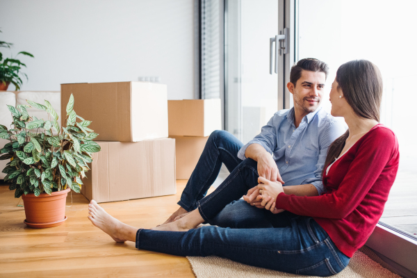 Young couple in love moving in a new home, sitting on the floor and looking at each other.