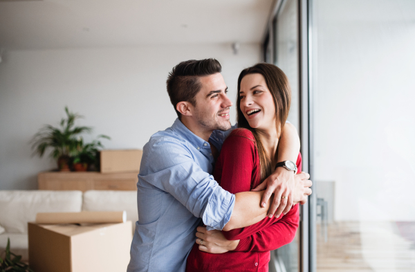 Young happy couple in love standing by the window at home, laughing and hugging.