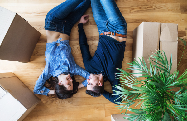 A top view of young couple with cardboard boxes lying on the floor, moving in a new home.