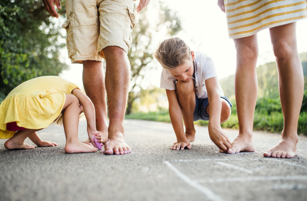 A midsection of young family with small children standing barefoot on a road in summer in countryside.