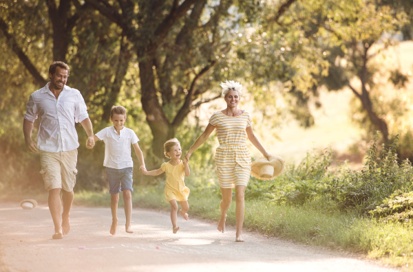 A young family with small children running barefoot on a road in summer nature.